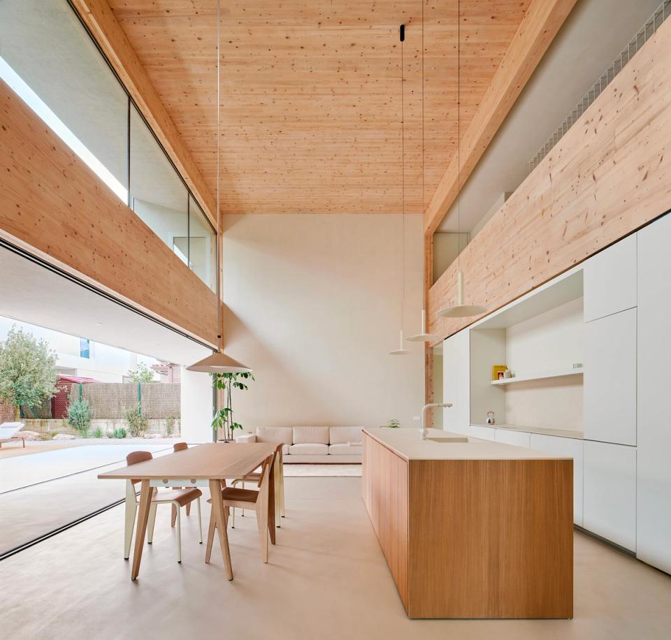 House in Girona with a double-height interior space fully open to the garden and natural light. This house in Girona incorporates natural wood, large glazed surfaces, and integrated solar protection to achieve comfort, spaciousness, and a strong connection with the outdoors