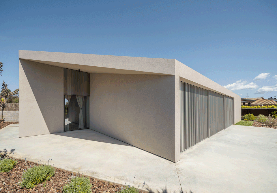This single-family home stands out for its minimalist and geometric architecture, defined by clean lines, pure volumes, and a homogeneous material palette that reinforces a sense of order and serenity. Large openings protected by vertical slats allow natural light control while preserving privacy, creating a contemporary, functional project perfectly integrated into the residential surroundings.