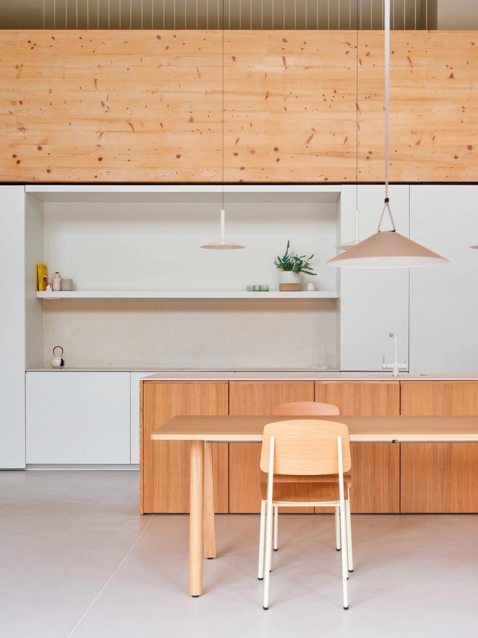 House in Girona with an open layout connecting the kitchen, relaxation spaces, and common areas through continuous materials and natural light. This house in Girona integrates wood, custom-made furniture, and flexible spaces to create warm, functional, and contemporary architecture