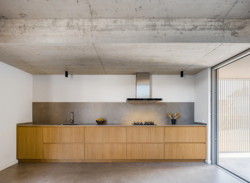 The kitchen of this single-family home reflects a functional and elegant architecture, with a minimalist composition that combines exposed concrete, stainless steel, and natural wood. Open spaces, natural light, and clean lines create a contemporary and welcoming atmosphere designed to integrate design, comfort, and functionality into everyday living.