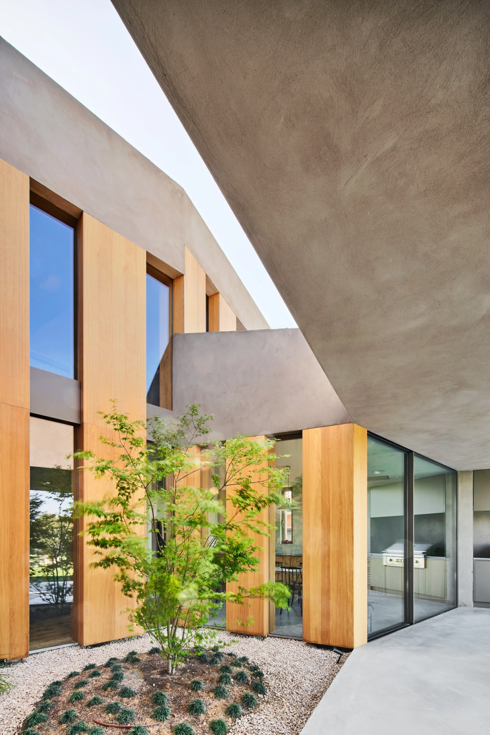 Geometric volumes, natural wood cladding, and the presence of interior courtyards define the essence of this contemporary single-family home. The architecture is committed to open, luminous spaces connected to the exterior, creating a warm, elegant atmosphere integrated into the surroundings.