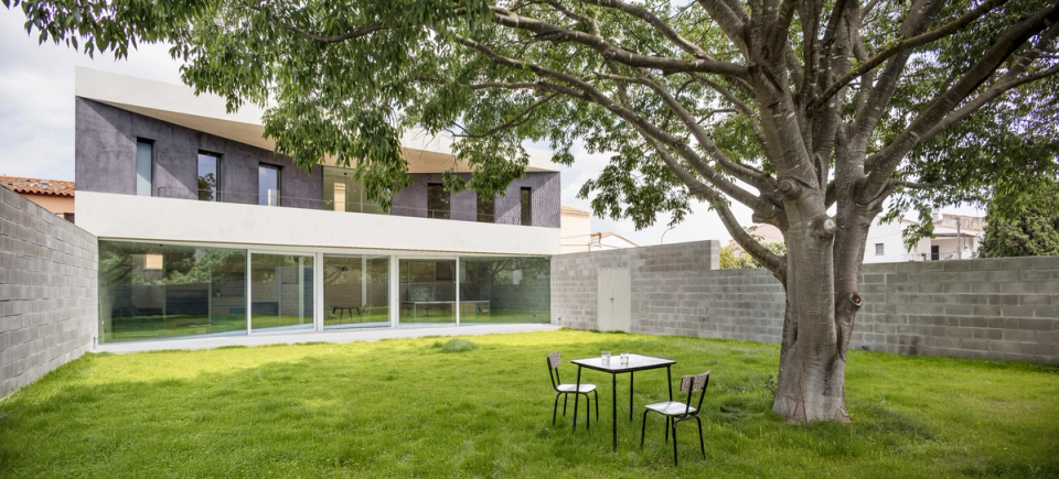 Outdoor space of a detached single-family home with a private garden, large glass surfaces, and modern architecture with horizontal lines. The house opens toward the exterior to enhance natural light, garden views, and an open and comfortable residential experience.