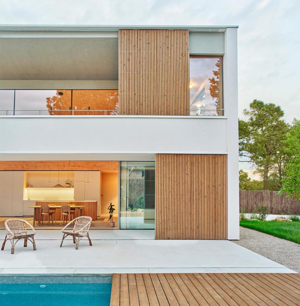 House in Girona with a contemporary façade and open spaces connecting the interior area with the terrace and swimming pool. This house in Girona combines natural wood, large windows, and a fluid layout to enhance natural light and outdoor living