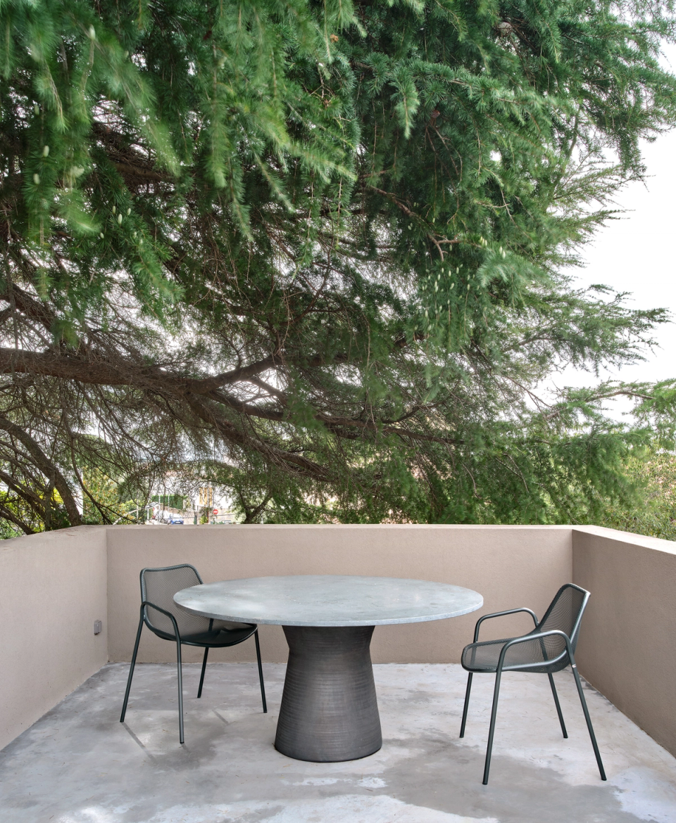 Ceramic and natural stone table for summer living.housing renovation with an outdoor terrace designed as a calm space to enjoy fresh air and vegetation. The renovation combines neutral materials, simple furniture and a connection with nature to create a relaxed and comfortable atmosphere.