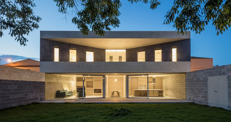 Contemporary detached single-family home with a façade open to the garden, large windows, and an interior layout connected to the outdoors. Night lighting highlights the architectural lines, open-plan spaces, and modern character of the residential project.