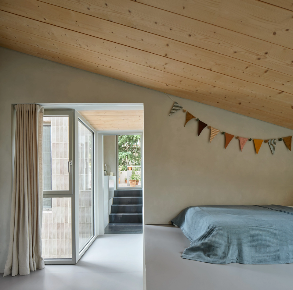 Housing renovation with an attic bedroom connected to a courtyard that acts as a source of natural light. The renovation takes advantage of the sloped volume, warm materials and the connection to the outdoors to create a cozy and comfortable space.