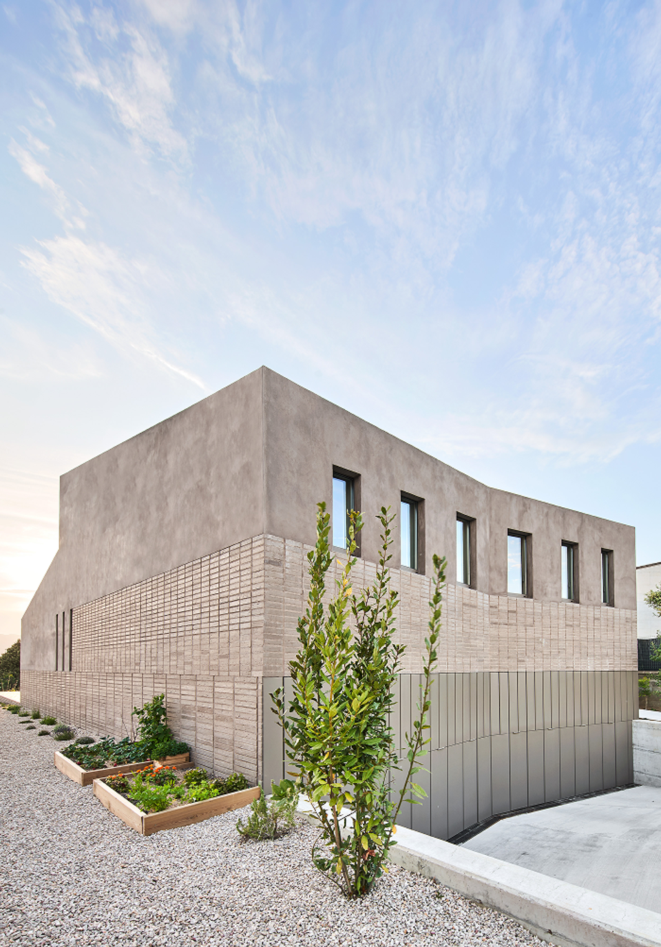 The façade of this single-family home stands out for its geometric composition and the use of textured materials that provide depth and character to the architectural ensemble. Clean volumes and vertical openings reinforce a contemporary, elegant aesthetic integrated into the surroundings.