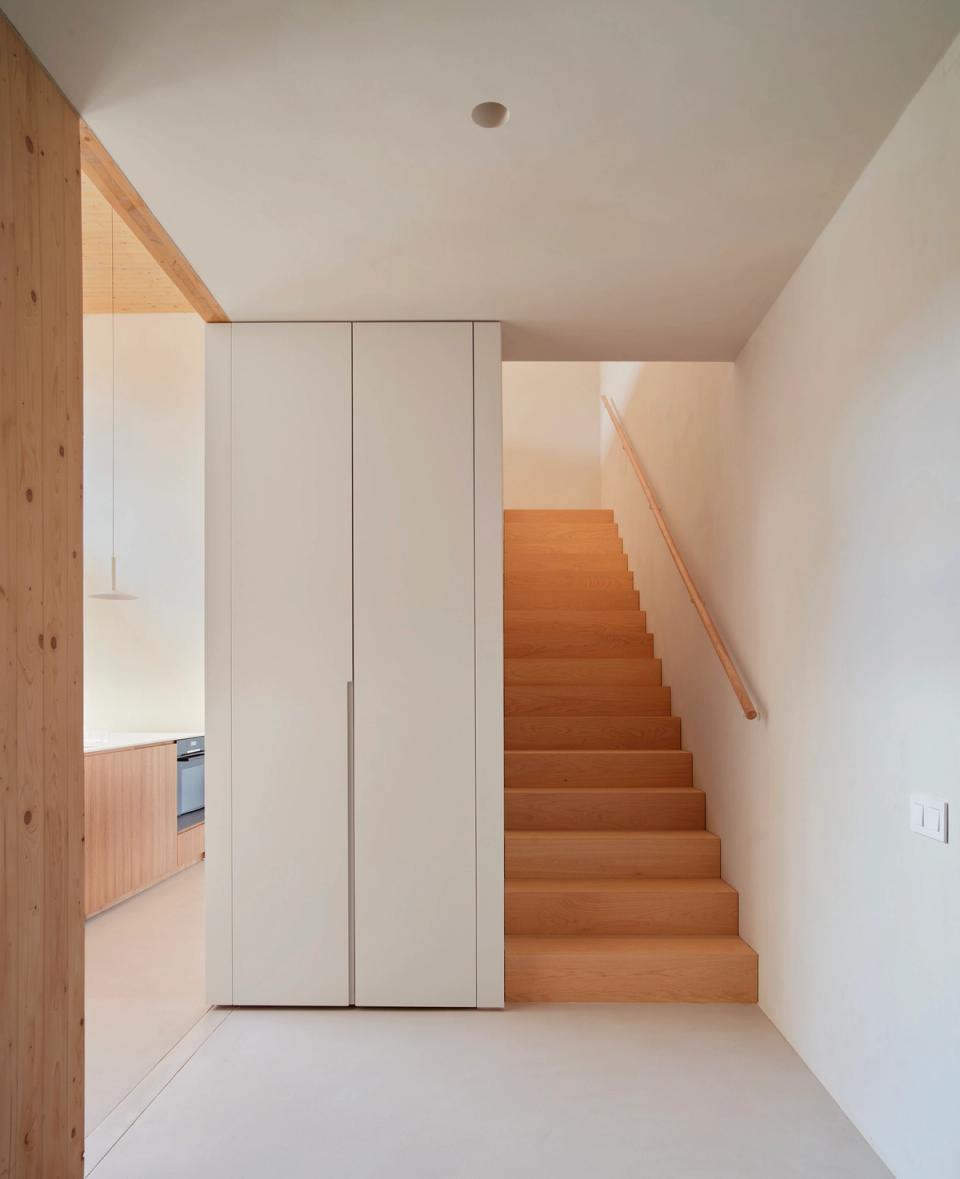 House in Girona with a wooden staircase integrated into a functional and minimalist layout connecting the different floors of the home. This house in Girona emphasizes natural materials, bright spaces, and organized architecture that enhances interior circulation