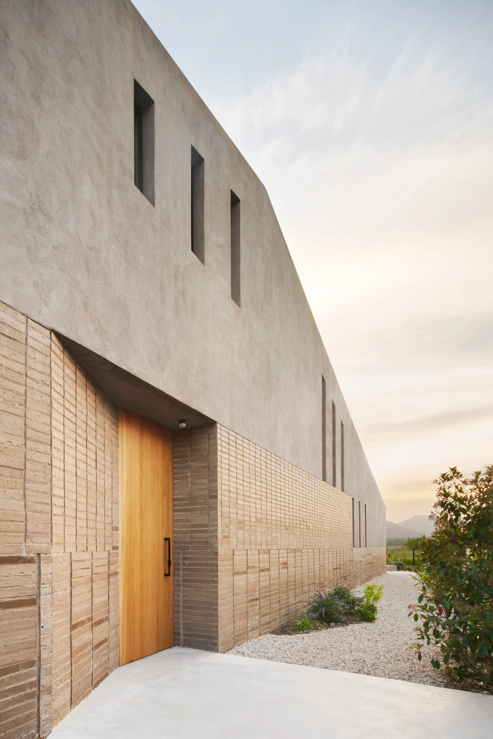 The façade of this single-family home combines clean volumes and textured materials to create a sober and contemporary architectural image. Vertical openings and the integration of landscaping bring light, rhythm, and a balanced connection with the surroundings.