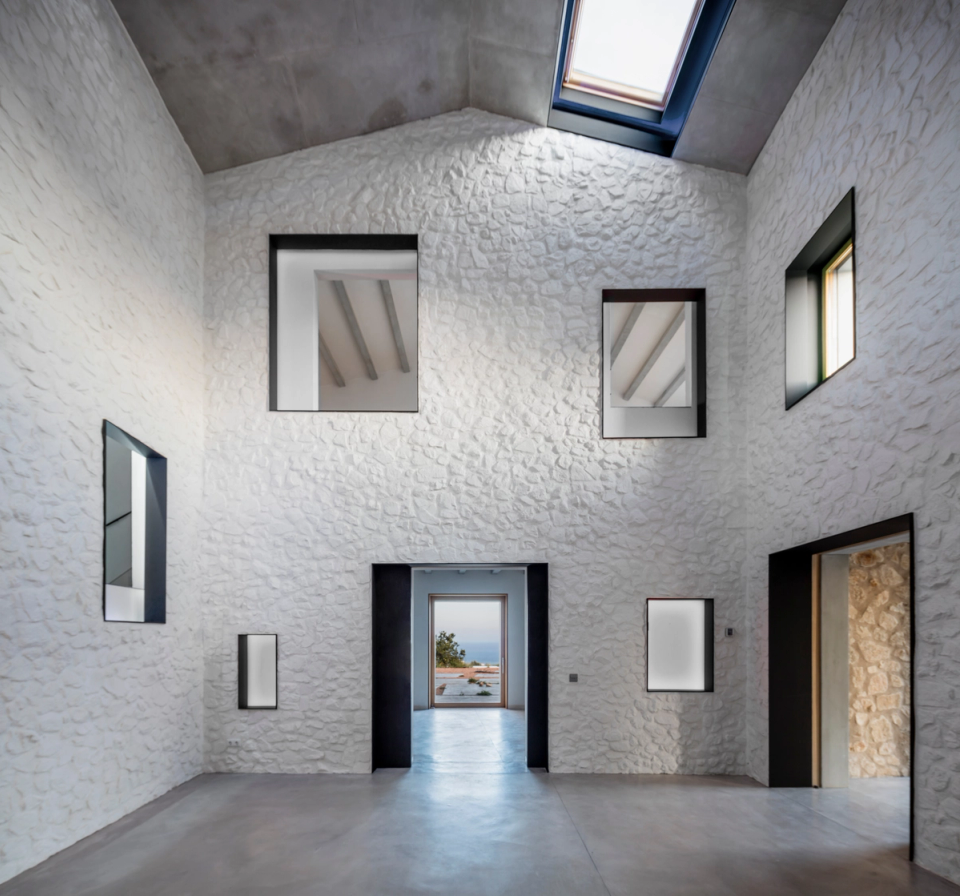 Interior hallway of a comprehensive renovation with contemporary architecture defined by natural light, sloped ceilings, and exposed concrete beams. Integrated skylights enhance the brightness of the spaces and reinforce the sense of spaciousness and visual continuity. Minimalist finishes combined with natural wood carpentry and clean lines create an elegant, functional, and timeless atmosphere. This full renovation stands out for the balance between modern design, comfort, and the careful integration of noble materials.