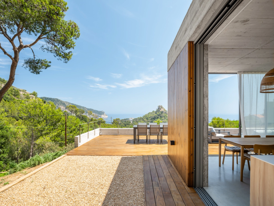 This single-family home in Begur takes advantage of its privileged location to fully open itself to the landscape and views of the Mediterranean Sea. The wooden terraces, large sliding openings, and the combination of exposed concrete with natural cladding create a contemporary architecture integrated with the surroundings, designed to enhance natural light, ventilation, and the constant relationship between interior and exterior.