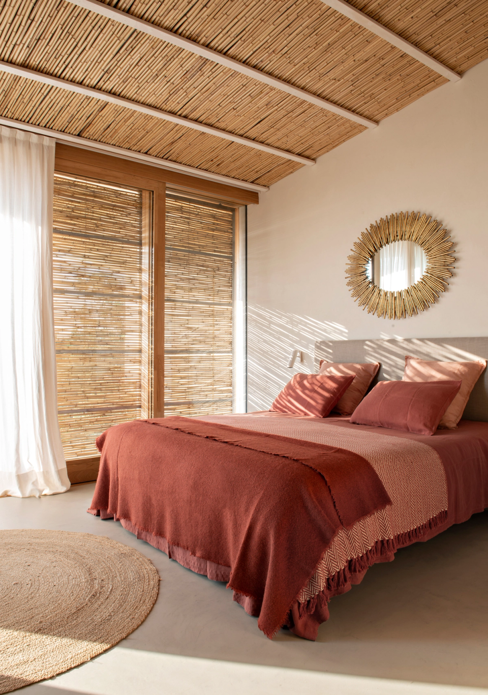 Bedroom of a detached house with a warm and relaxing atmosphere created through natural materials, earthy tones and soft light filtered through natural fiber enclosures. Reed-clad ceilings, natural wood carpentry and Mediterranean-inspired décor reinforce the sense of comfort, serenity and connection with the surrounding natural environment.