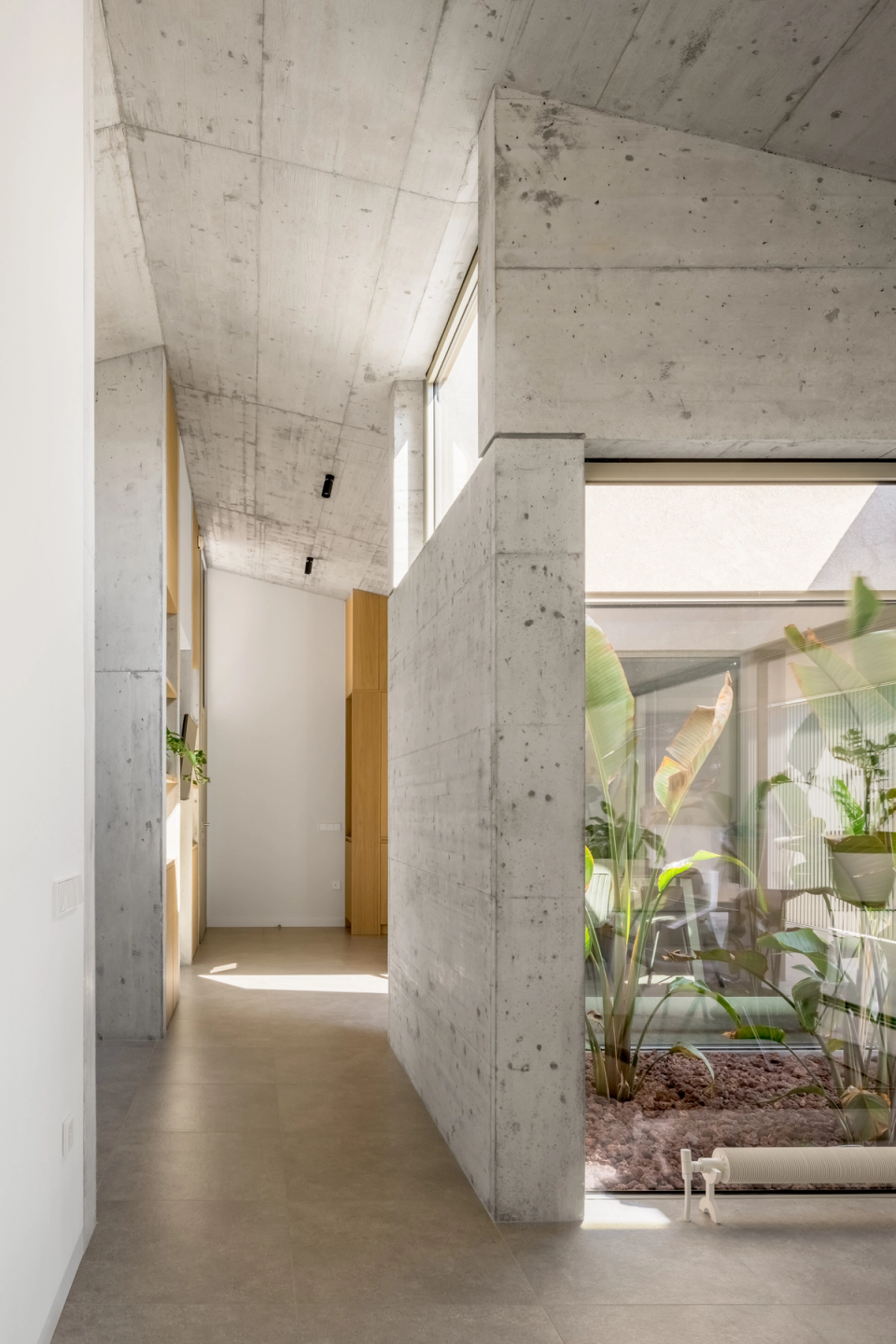 The interior of this single-family home embraces an honest and contemporary architecture, where exposed concrete, natural light, and open spaces define a serene and sophisticated atmosphere. The integration of an interior courtyard with vegetation provides visual spaciousness and a connection with the outdoors, enhancing comfort and spatial quality.