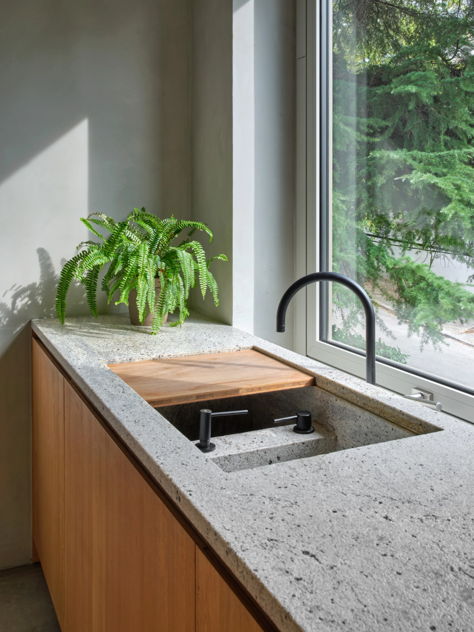 Housing renovation with a kitchen designed to meet everyday needs with functionality and simplicity. The renovation combines natural stone, wood and exterior light to create a warm, practical space connected to its surroundings