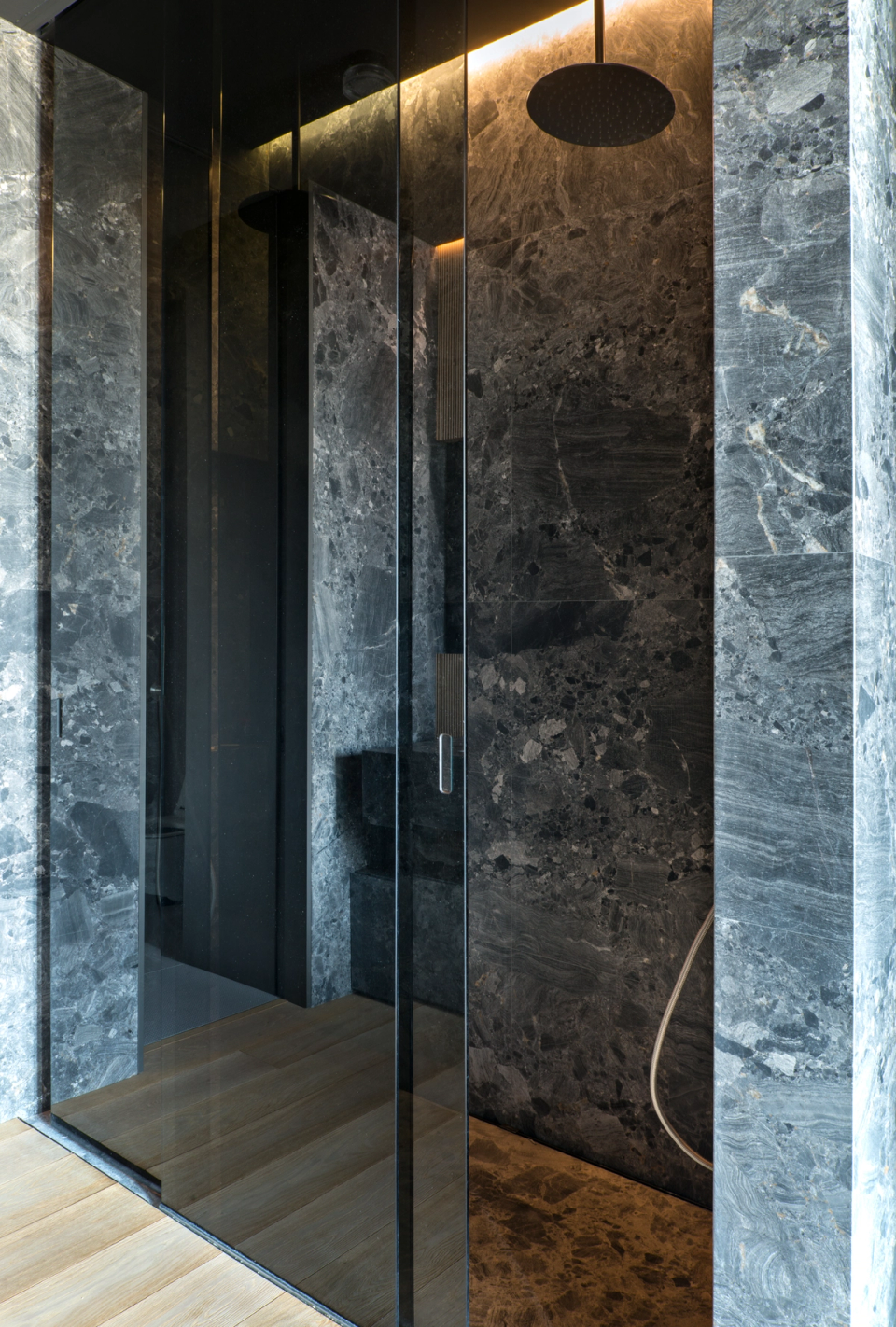 The interior renovation of this shower embraces an elegant and contemporary aesthetic, where dark natural stone becomes the main protagonist of the space. Large-format continuous surfaces combined with minimalist profiles and integrated lighting generate a sophisticated and immersive atmosphere. The interplay of reflections on glass and mineral textures adds visual depth and reinforces the sense of exclusivity, transforming the bathroom area into a wellness space with a strong architectural identity.