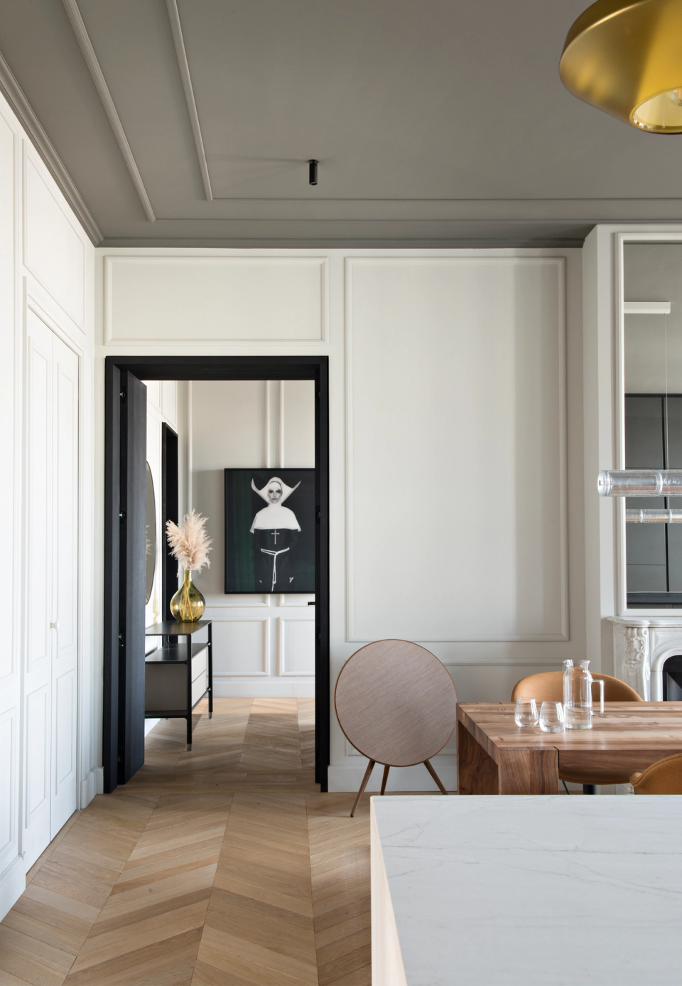 The interior renovation of this home redefines the spaces with a contemporary proposal that respects the original character of the architecture. Classical moldings, ornamental ceilings, and herringbone wood flooring are combined with contemporary design pieces, neutral tones, and black details that add depth and elegance. The new open layout and the visual continuity between rooms enhance the feeling of spaciousness, brightness, and sophistication throughout the interior.