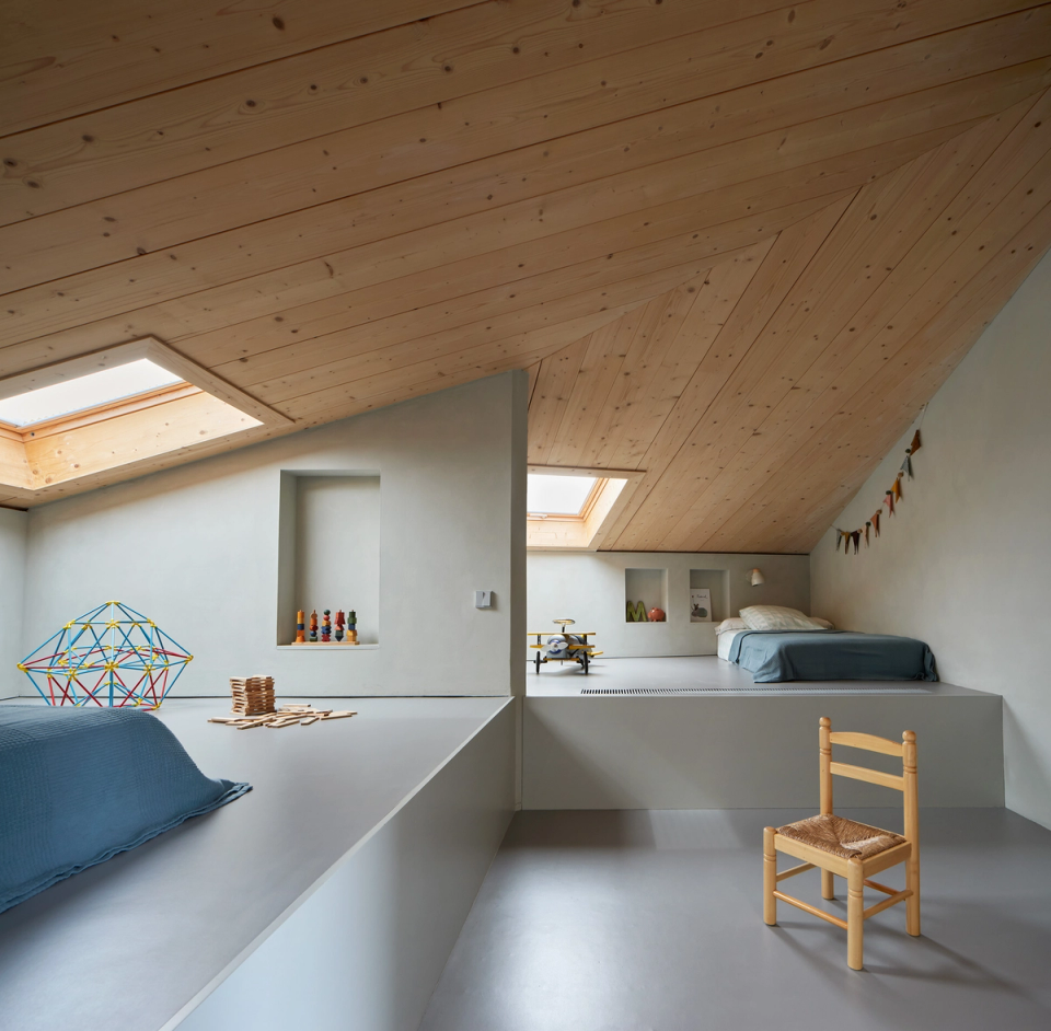 Housing renovation with an attic floor designed as a flexible and bright space for rest and play. The renovation takes advantage of zenithal light, wooden ceilings and an open layout to create a warm, functional and family-friendly atmosphere.