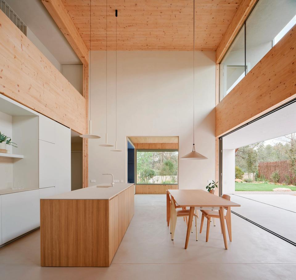 House in Girona with an open-plan living area and large sliding enclosures that fully connect the interior with the garden. This house in Girona combines open spaces, natural light, and warm materials to create a contemporary and comfortable atmosphere