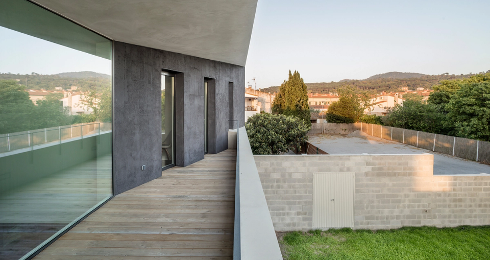 The upper floor is presented as a compact and restrained volume housing the private areas of the home. Vertical openings and the longitudinal terrace protected by the large overhang reinforce the connection with the outdoors, providing light, privacy, and landscape views. The combination of light and dark materials emphasizes the project’s contemporary and minimalist character.