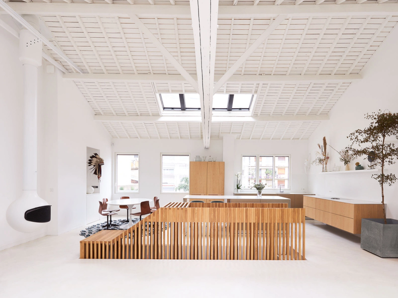 Spacious and bright living room, with white tones, fireplace hanging in a modern oval shape, and in the middle of the room access to the wooden stairs. This reform of this luxury apartment in Paris by 05 AM architecture.