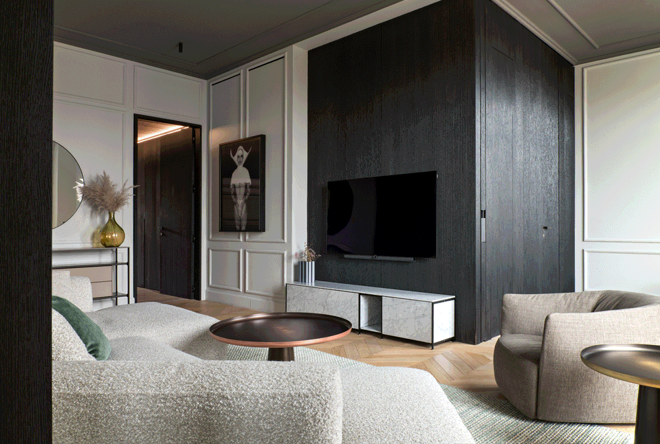 The interior renovation of this living area combines classical elegance and contemporary design through a sophisticated and functional proposal. Dark finishes add depth and contrast with the original molded walls, while furniture with organic lines and soft textures creates a warm and welcoming atmosphere. The intervention reinforces the visual continuity of the spaces and enhances natural light to create a balanced, modern, and timeless environment.