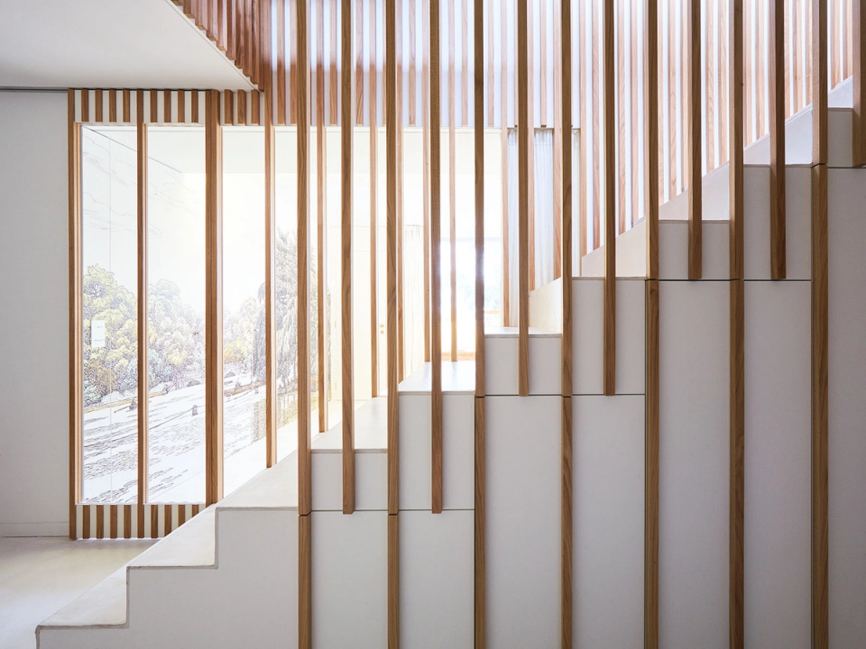 The renovation embraces a clean and functional architecture where every element contributes to the visual coherence of the home. The staircase, integrated within a composition of vertical wooden slats, creates an elegant filter for natural light, bringing depth, lightness and a subtle connection between the different interior spaces.
