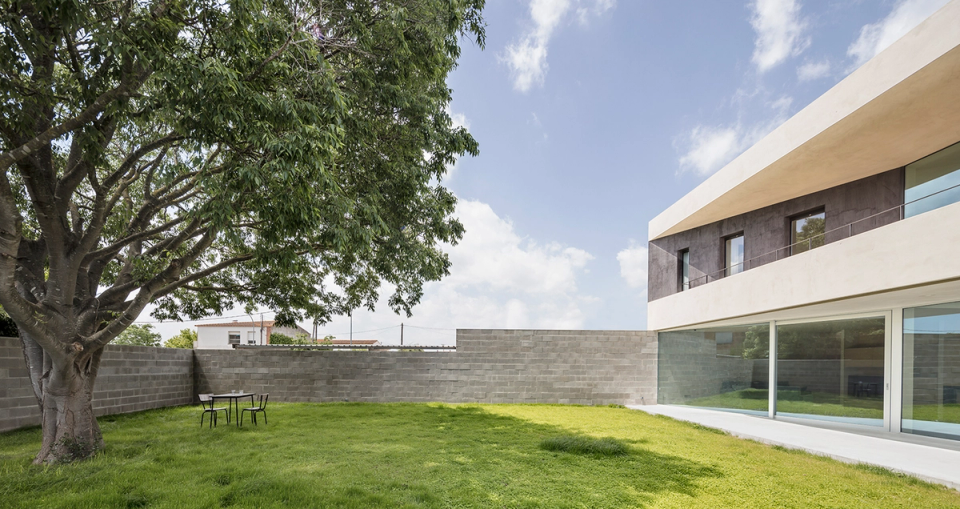 Exterior garden of a detached single-family home with large windows and contemporary architecture integrated into a natural environment. The project enhances the relationship with green space, natural light, and outdoor living through an open and functional layout.