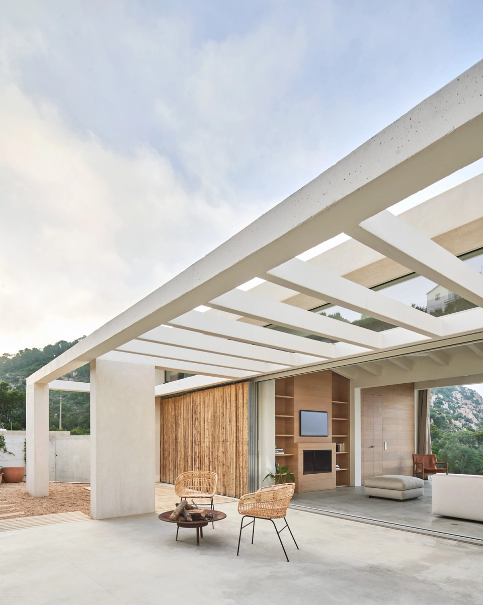 This single-family home redefines the relationship between interior and exterior through open and permeable architecture that enhances natural light and landscape views. The large structural pergola creates a protected outdoor space that acts as an extension of the living room, generating a fluid transition between the different areas of the house. Natural wood cladding, minimalist lines, and continuous materials reinforce the home’s contemporary Mediterranean aesthetic. This single-family home stands out for its spaciousness, integration with the surroundings, and spaces conceived for enjoying outdoor living with comfort and naturalness.