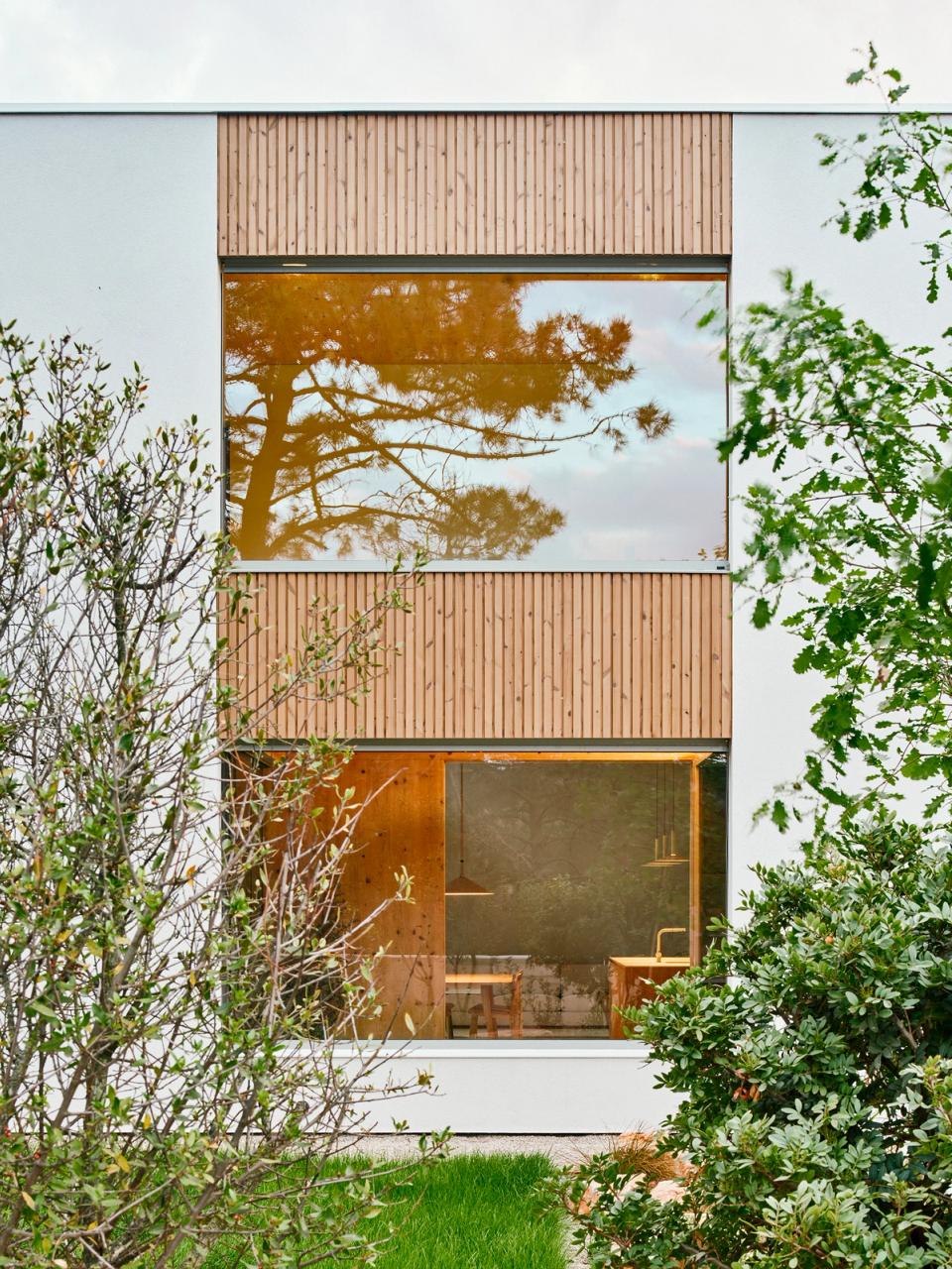 House in Girona with a clean-lined façade and natural wood cladding that reinforce the connection with the landscape and outdoor light. This house in Girona combines large windows, warm materials, and contemporary architecture designed to naturally integrate interior and exterior spaces