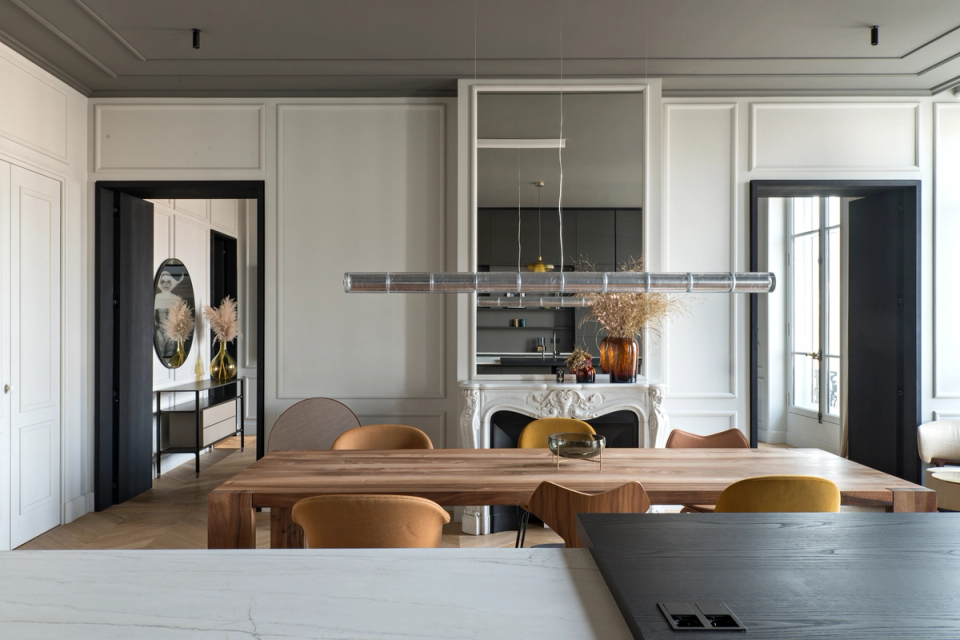 The interior renovation of this dining room restores the classical essence of the home and combines it with contemporary elements to create a sophisticated and balanced space. Original moldings, an ornamental fireplace, and decorative ceilings coexist with modern furniture, dark finishes, and sculptural lighting that adds personality to the overall design. The intervention enhances natural light and the connection between rooms, generating a warm, elegant, and functional atmosphere.