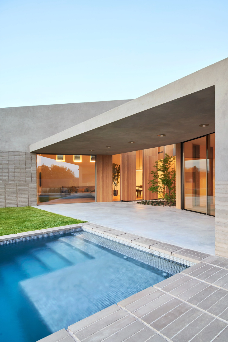 The outdoor area of this single-family home merges architecture and landscape through an elegant and open proposal. Large windows, continuous porches, and the swimming pool reinforce the connection between interior and exterior spaces, bringing spaciousness, light, and comfort.