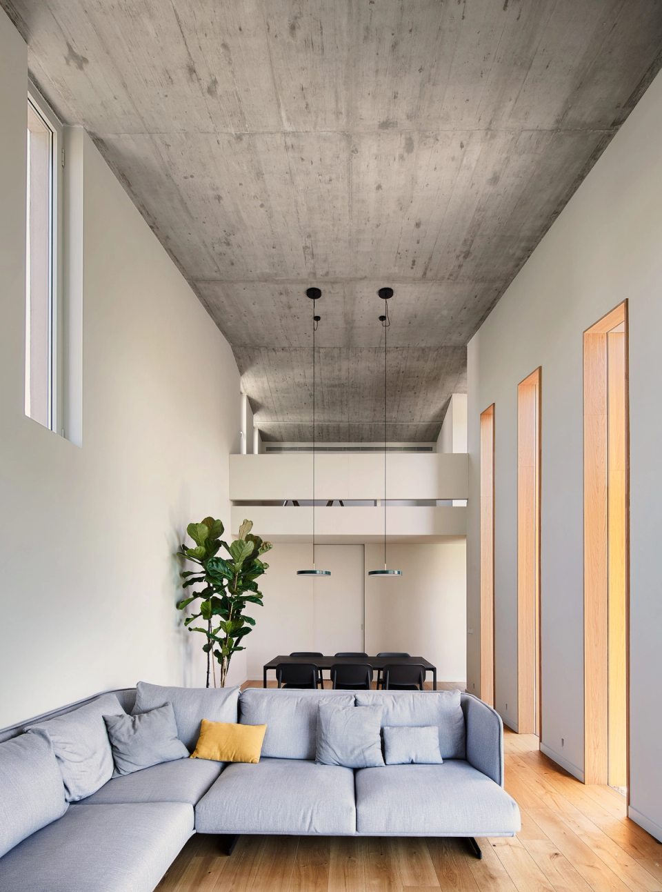This single-family home stands out for its spacious and minimalist interiors, defined by high ceilings, exposed concrete, and natural light. The combination of warm materials and clean lines creates a contemporary, elegant, and functional atmosphere.