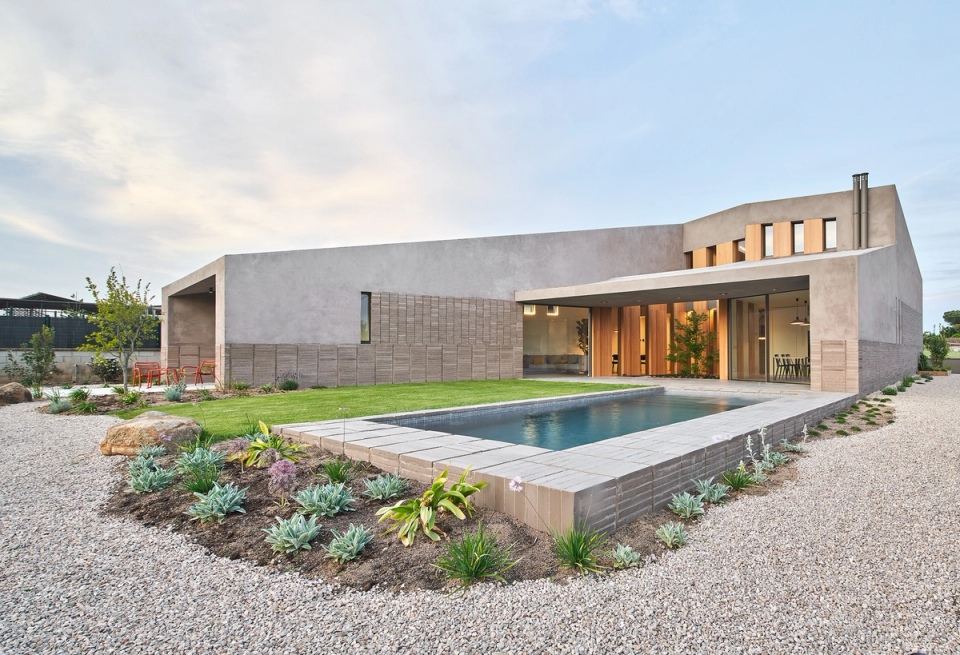 This single-family home stands out for its contemporary architecture with clean lines and natural materials that integrate elegantly into the surroundings. The longitudinal swimming pool structures the outdoor area and visually connects with the interior spaces through large glazed openings that enhance natural light. The Mediterranean garden and mineral finishes provide balance, serenity, and a fluid relationship between interior and exterior.