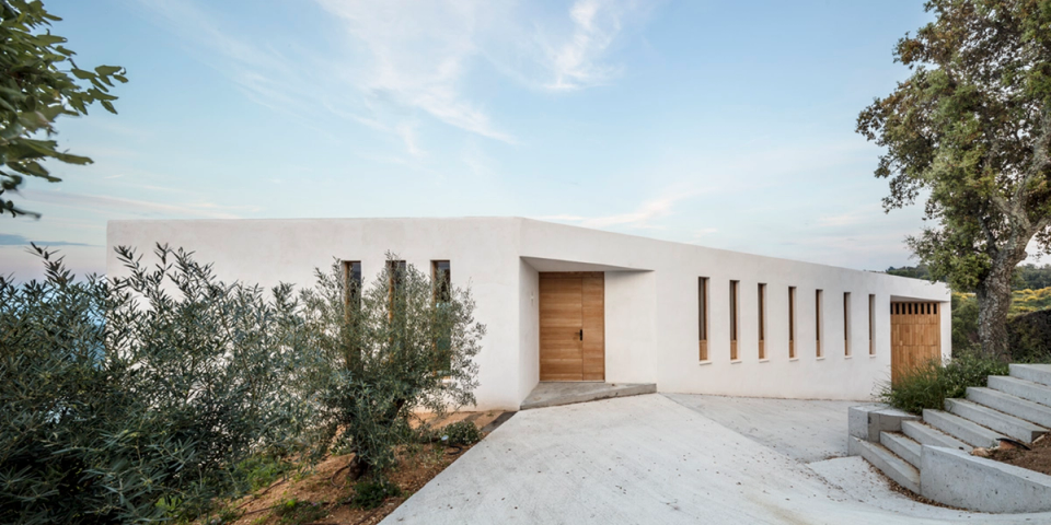 Main façade of a contemporary detached house with horizontal volumes and minimalist finishes, conceived to integrate discreetly into the natural landscape. Vertical openings, natural wood and landscaped outdoor spaces bring light, rhythm and warmth to an elegant and functional architecture.