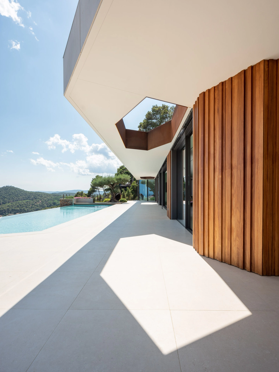 Detached single-family home integrated into the landscape with a natural stone façade that dialogues with the Mediterranean surroundings and reinforces the connection with the site’s topography. The exterior pathway, open to panoramic views, combines noble materials such as corten steel and stone to create a sober, contemporary architecture perfectly adapted to the natural environment.