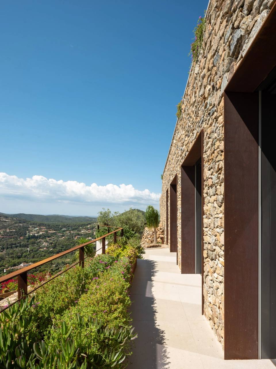 Detached single-family home with contemporary architecture marked by the relationship between volumetry, light, and landscape. The cantilevered porches, natural wood cladding, and large openings create elegant and protected outdoor spaces integrated with the infinity pool and open views of the Mediterranean surroundings.