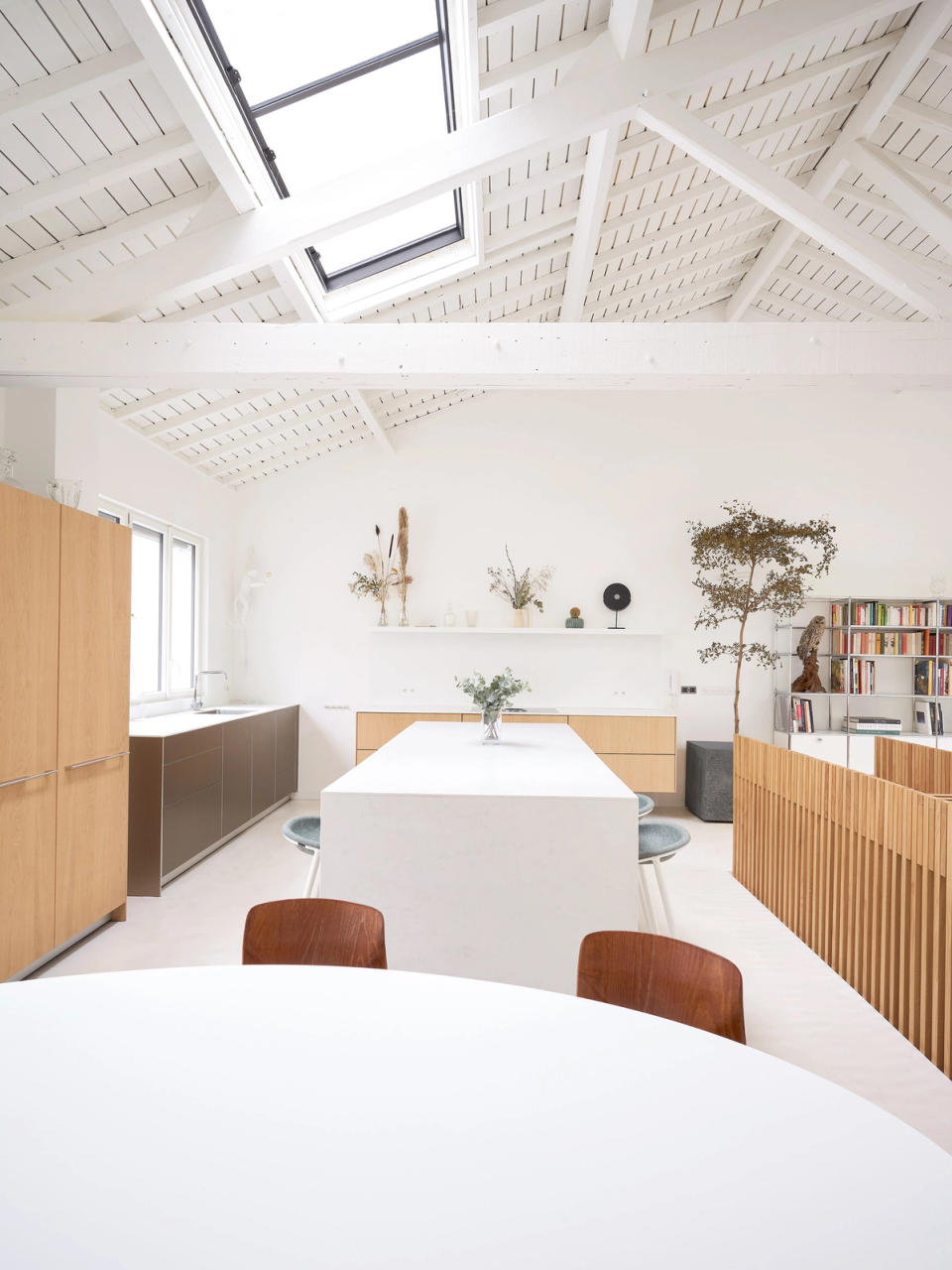 The full renovation of this kitchen embraces a minimalist and bright design, featuring natural wood cabinetry and an open layout that enhances functionality and visual continuity. The restored roof with exposed beams and skylights maximizes natural light and brings warmth to the atmosphere.