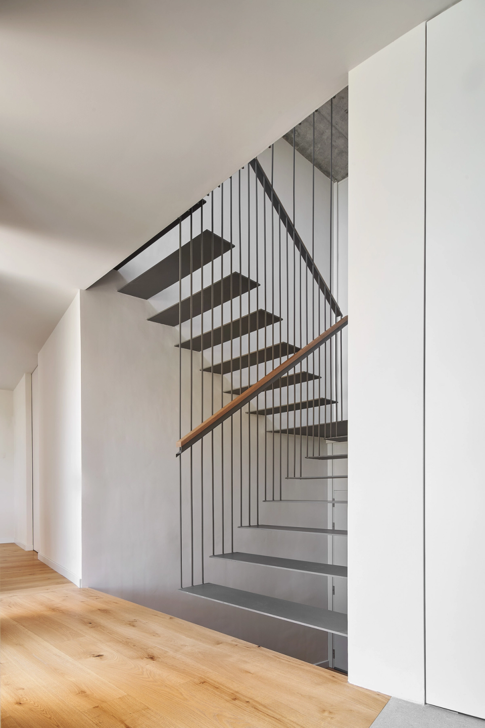 The staircase in this single-family home becomes a key architectural feature thanks to its light and minimalist design. The combination of metallic structure, natural wood, and open spaces reinforces the sense of spaciousness and visual continuity within the interior.
