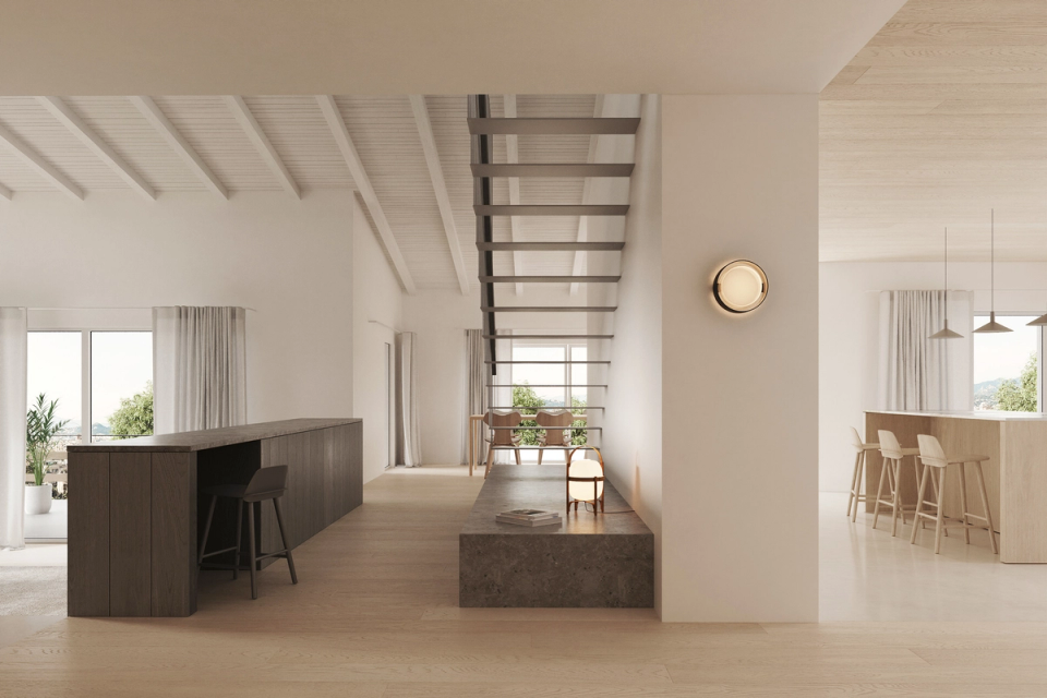 Interior renovation with a double-height living room defined by sloped ceilings, clean lines, and a sculptural staircase integrated into the space. This interior renovation combines warm materials, natural light, and minimalist architecture to create an elegant and welcoming atmosphere.
