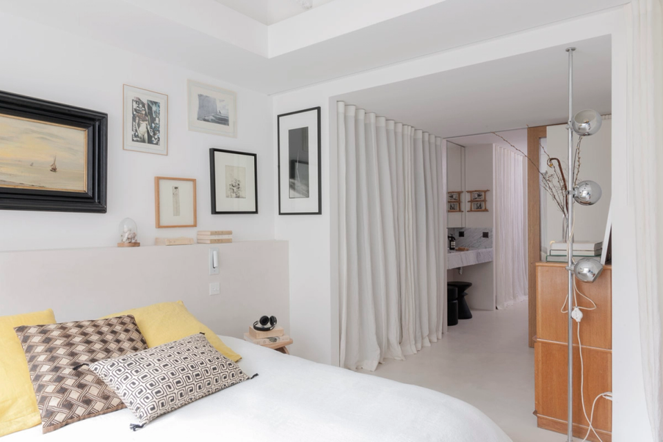 This full renovation embraces open and flexible spaces where natural light and soft textiles create a warm and welcoming atmosphere. The bedroom combines contemporary furniture, wall art and neutral tones with natural wood details that add personality and visual balance. Sliding curtains allow the spaces to be redefined according to daily needs, integrating the sleeping area, dressing room and bathroom with an elegant and functional aesthetic.