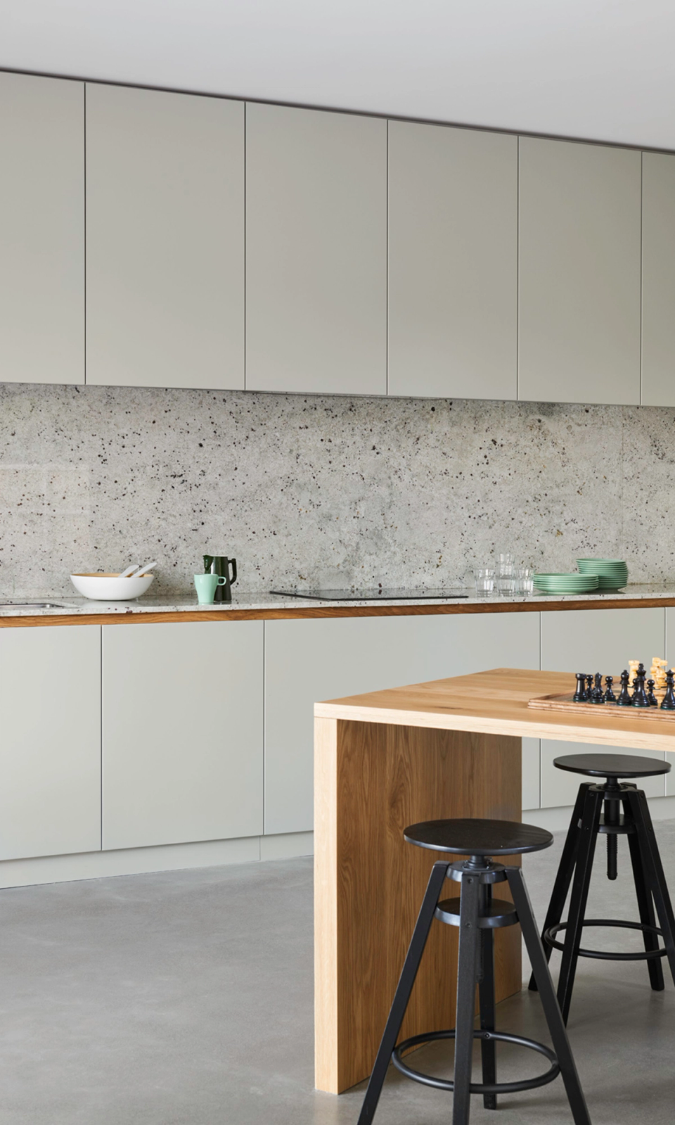 Modern kitchen in a detached single-family home with minimalist lines, integrated cabinetry, and neutral-toned finishes. The space combines functionality and contemporary design with natural materials, continuous surfaces, and an open layout designed for everyday living.