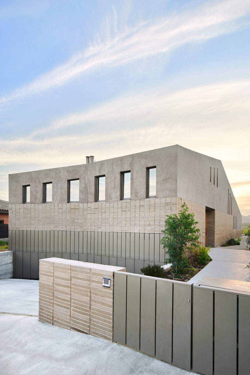 This single-family home features a sober and contemporary architecture defined by compact volumes, mineral textures, and a balanced composition of vertical openings. The combination of concrete, ceramics, and metallic finishes reinforces the elegant and timeless character of the architectural ensemble, discreetly integrated into its residential surroundings.