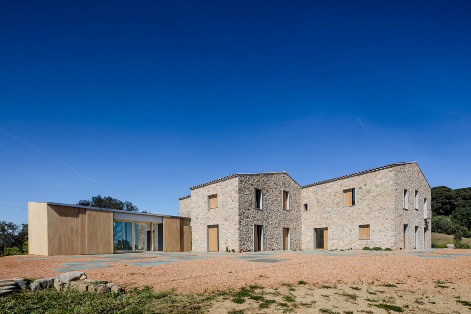 Complete farmhouse renovation with an architectural proposal that merges traditional architecture with a contemporary extension featuring minimalist lines and natural materials. The project restores the original stone structure, maintaining the authenticity and rustic character of the building while introducing new spaces with wooden façades and large glass enclosures that enhance brightness, efficiency, and comfort. The intervention creates a harmonious ensemble integrated into the landscape, where the comprehensive renovation respects the identity of the existing construction and transforms it into a modern, functional home adapted to current needs.