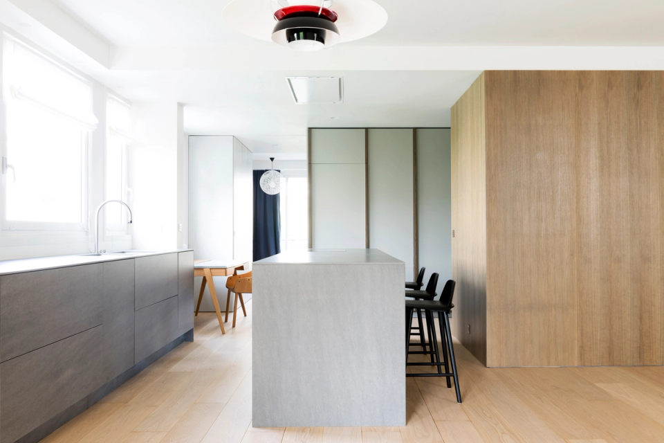 The interior renovation redefines the kitchen as a clean, functional space integrated into the living area. The combination of natural wood, mineral surfaces, and light tones brings balance and brightness, while the central island becomes the organizing element of the space, encouraging interaction between the kitchen and dining area.