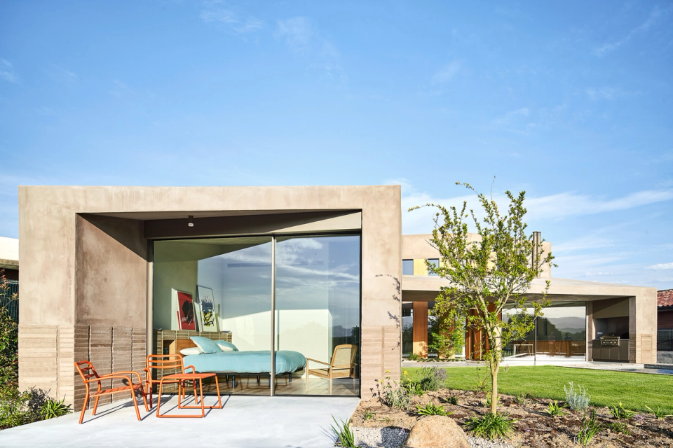 This outdoor space of the single-family home stands out for its direct connection between interior and garden, with large glass openings that enhance natural light and views. The combination of concrete, wood, and vegetation creates a contemporary architecture integrated into the surroundings.