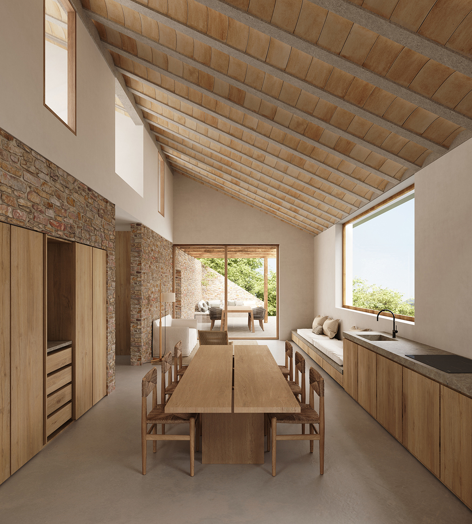 Interior spaces of the house in Tamariu defined by natural materials, sloped ceilings, and open, luminous architecture. The combination of stone, wood, and large openings creates a warm and timeless Mediterranean atmosphere, with a fluid relationship between the interior areas and the outdoor terraces.