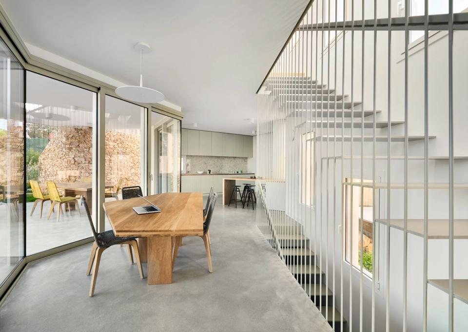 Detached single-family home with open and contemporary interiors combining natural light, visual spaciousness, and functional layout. The lightweight metal staircase and large windows strengthen the connection between interior and exterior spaces, creating a modern, warm, and elegant atmosphere.