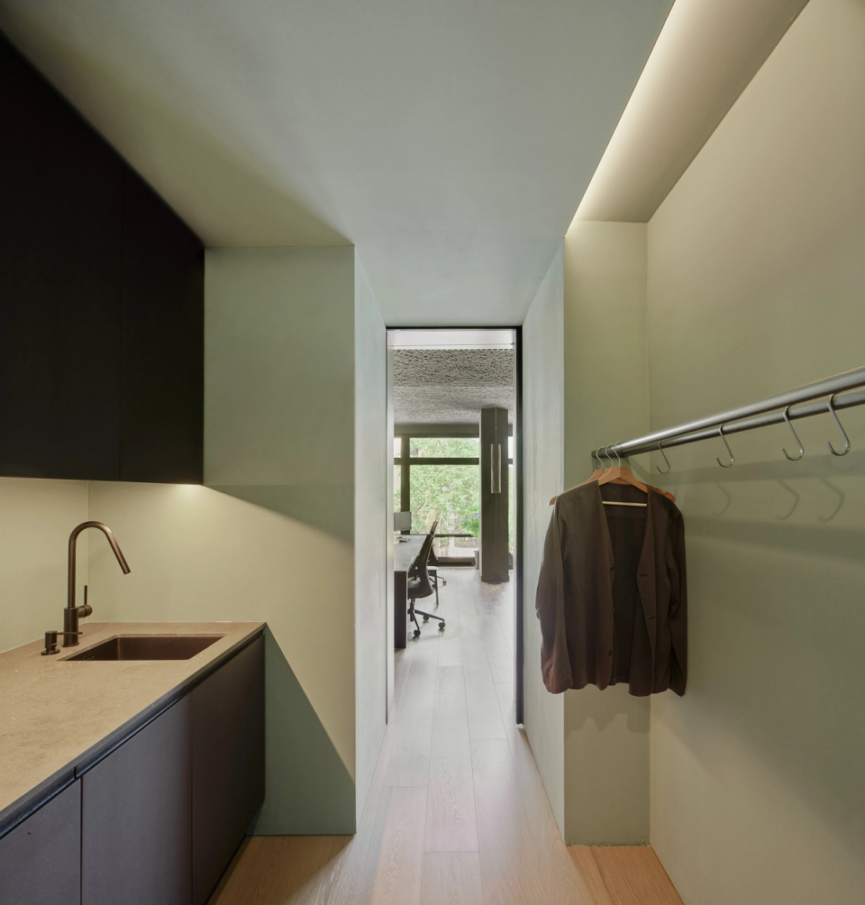 Reform of studio with a functional auxiliary area that integrates service and storage spaces within an ordered and minimalist layout. This studio renovation combines dark finishes, indirect lighting and continuous materials to create an elegant, practical and contemporary environment.