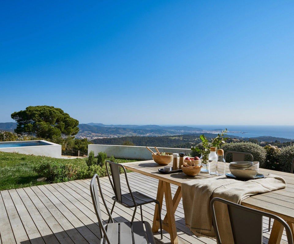Outdoor terrace of a detached house with panoramic views of the Mediterranean landscape and the sea. The space combines natural materials such as wood with an open layout that connects the home with its surroundings, creating an outdoor area designed to enjoy natural light, calmness and outdoor living.