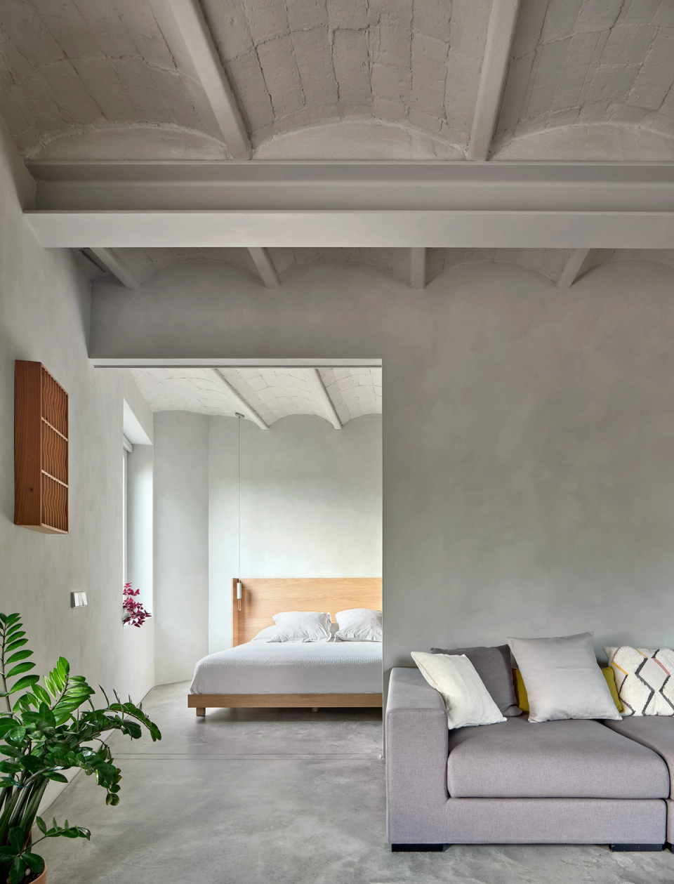Housing renovation with spaces visually connected through large interior openings that expand the perception of space. The renovation maintains material continuity and restores original elements to create a serene, bright and contemporary atmosphere.